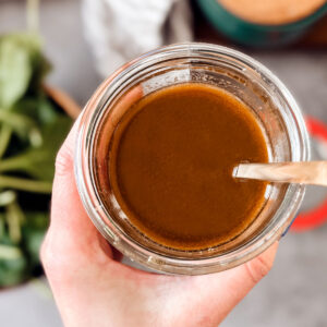 Hand holding jar of maple balsamic dressing.