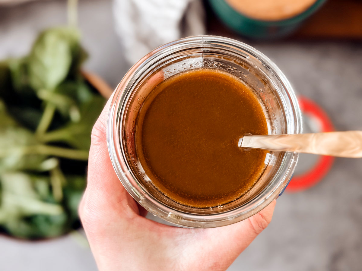 Hand holding out dressing in a jar.