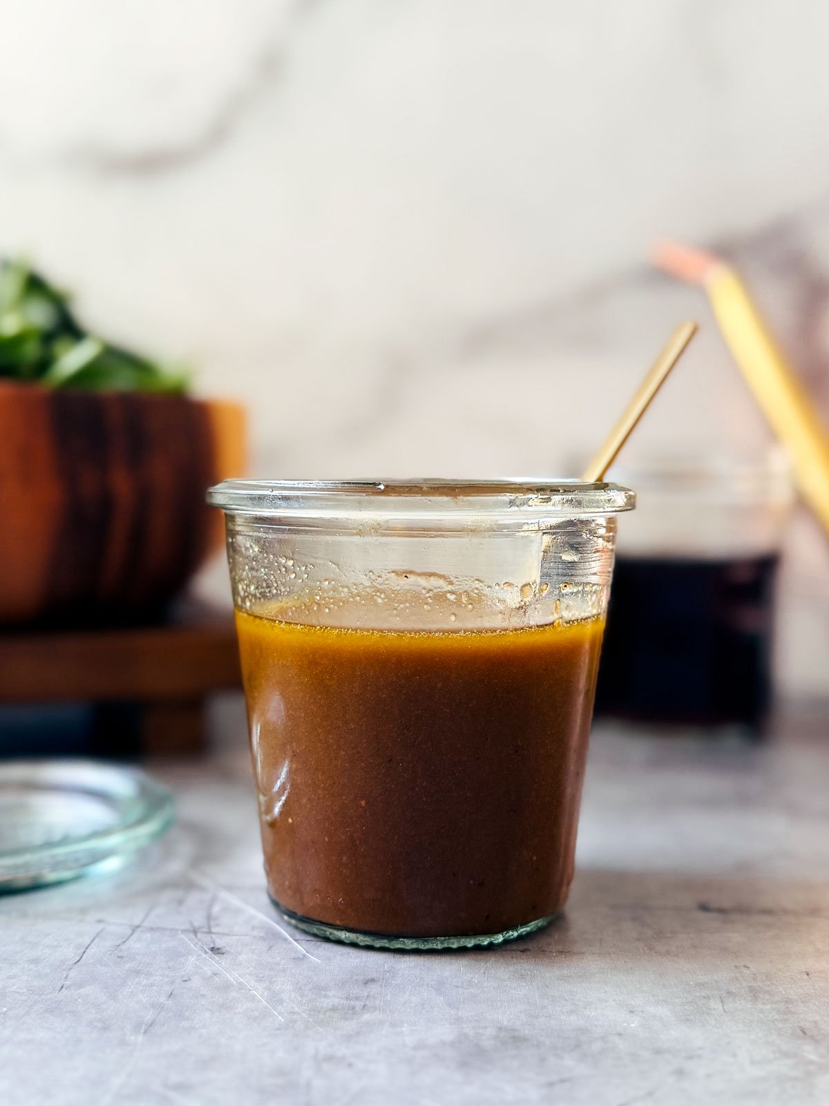 Small jar of maple balsamic dressing on a kitchen counter.