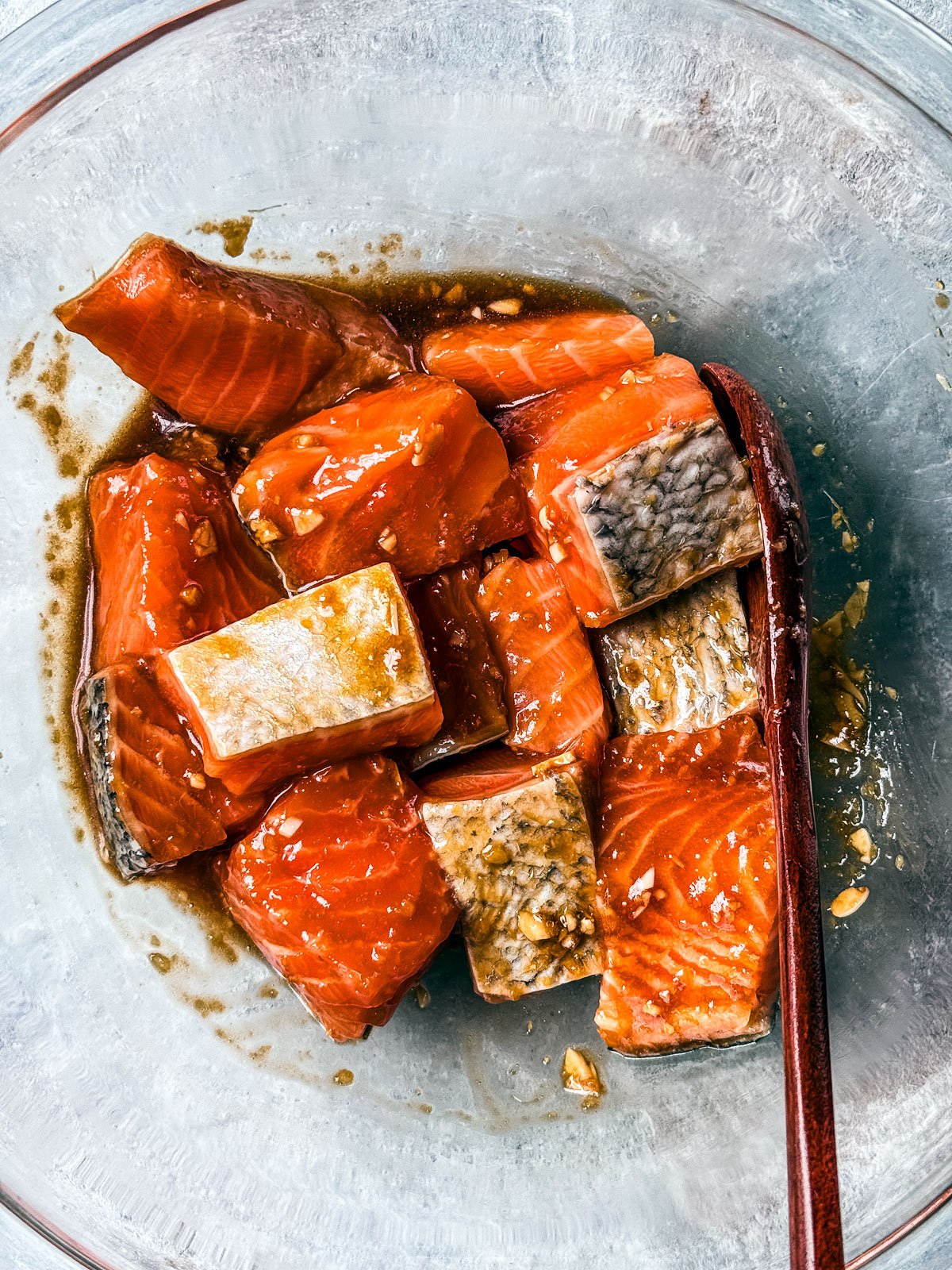 Salmon cubes marinating in a glass bowl.