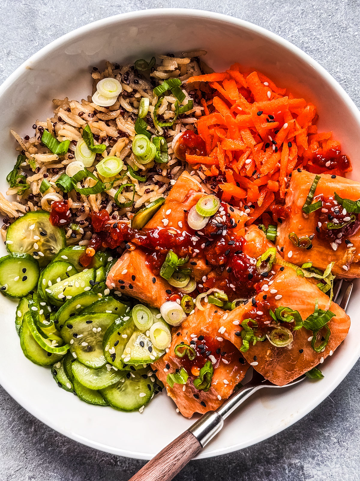 Rice bowl with salmon drizzled with chili sauce.