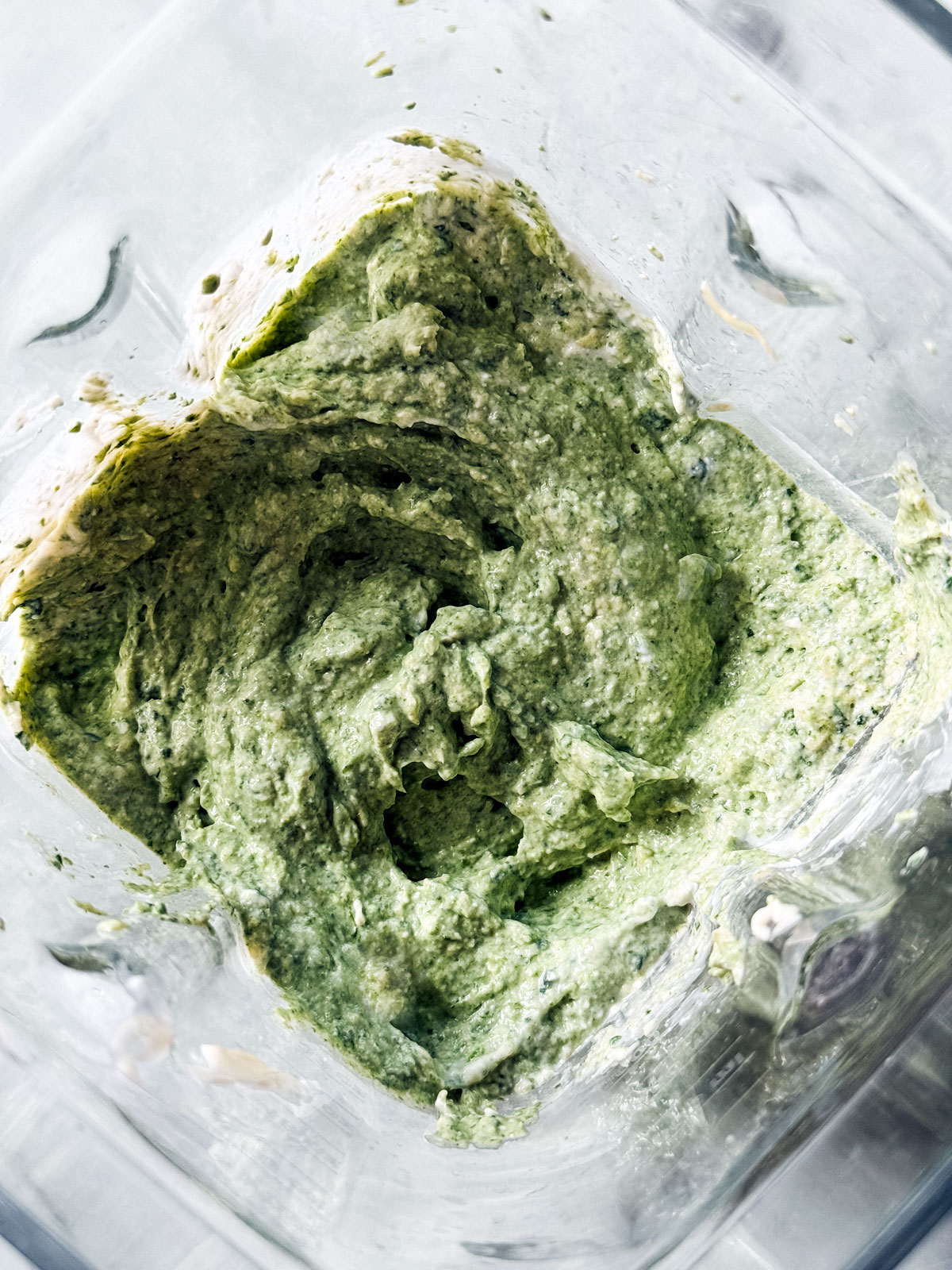 Bright green spinach and artichoke cottage cheese dip blended in a blender.