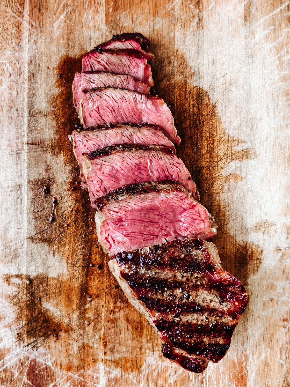 Sliced steak on a cutting board exposing a nice medium rare center.